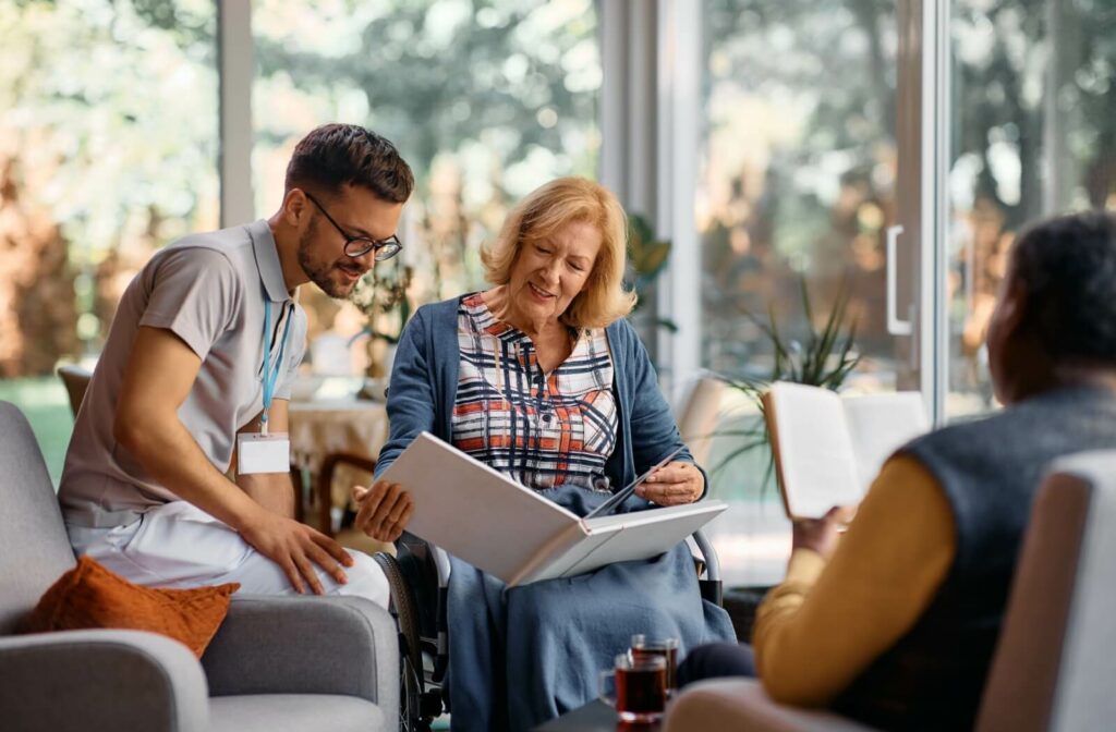 A senior reminiscing over old photos with a nurse at a memory care community.