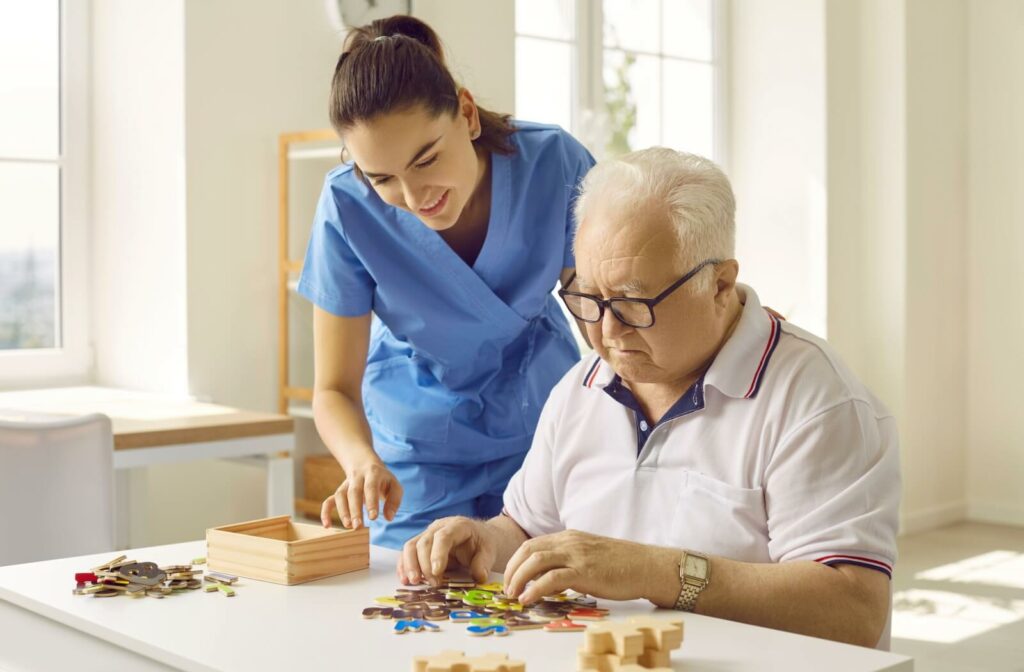  A memory care resident focuses on an activity that stimulates cognitive function with help from care staff.