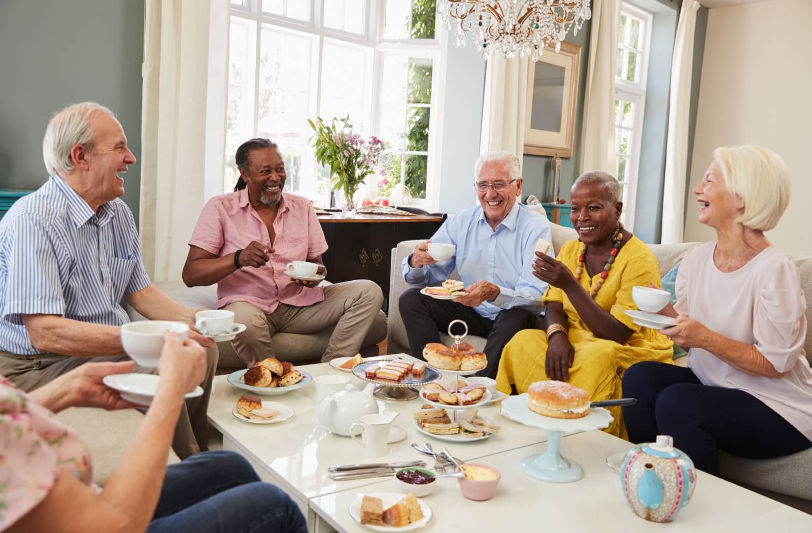 A group of seniors enjoy tea and a light snack together.