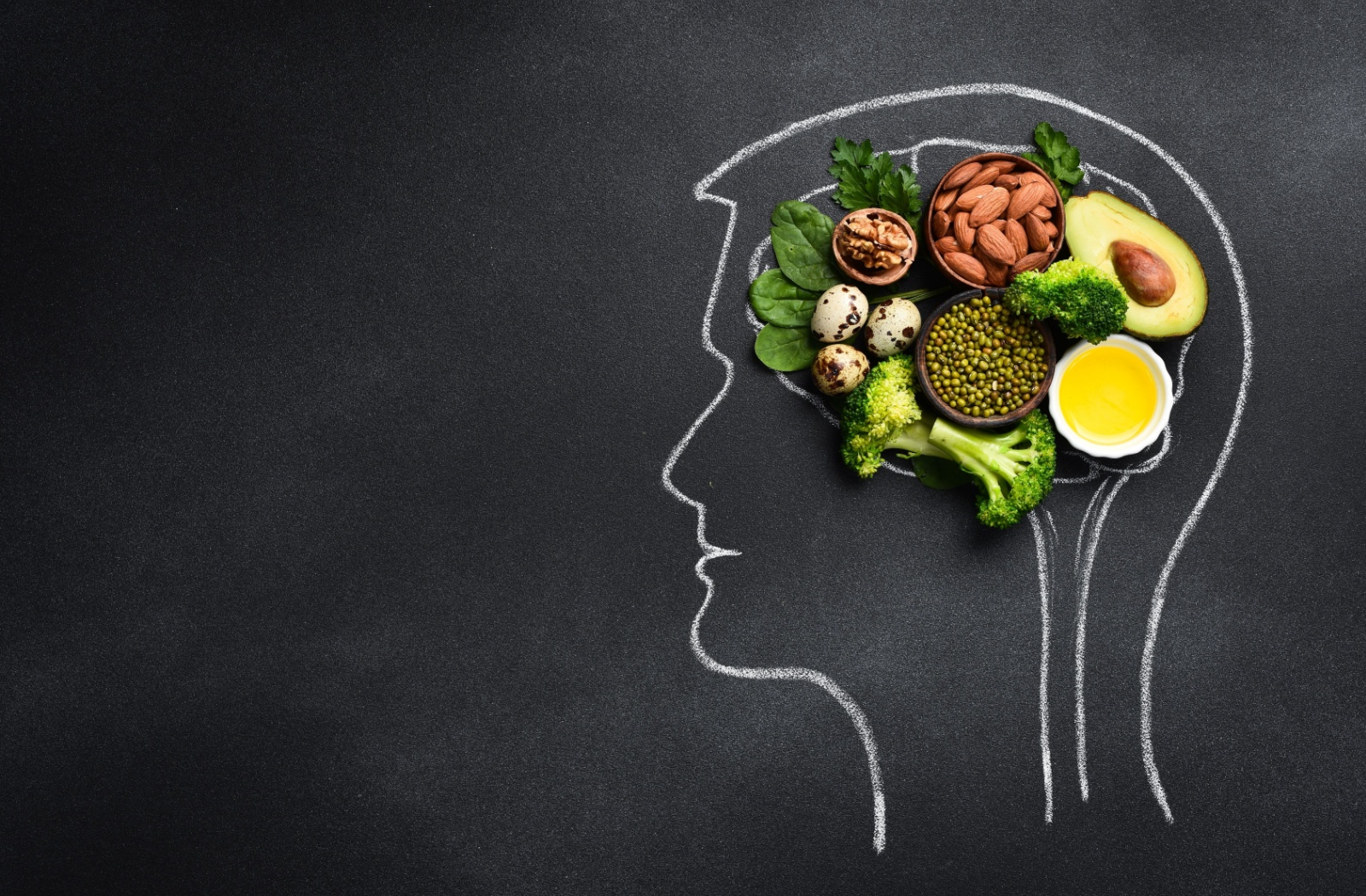 Healthy food for brain function and memory inside a chalk drawing of the brain on a black chalkboard.