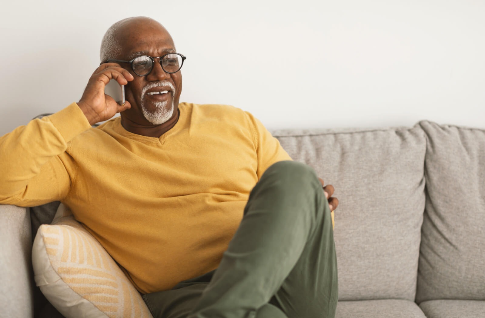 a senior sits on a couch chatting on a smartphone